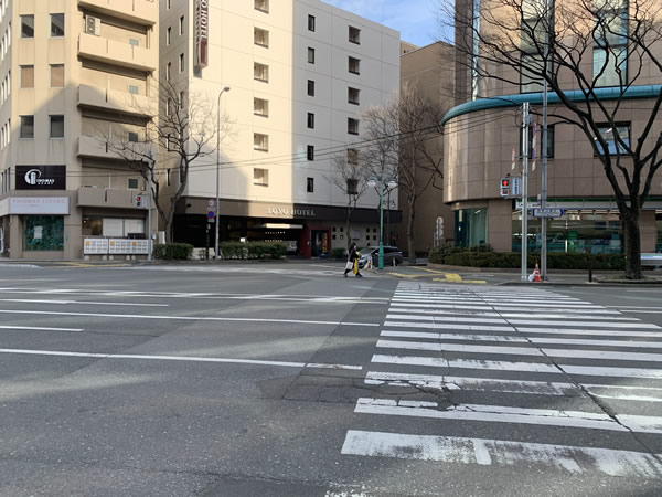 スクランブル交差点を右方向(渡った先はファミリーマート)に渡ります。そのまま正面に見える東洋ホテル側にさらに横断歩道を渡り、右折します。